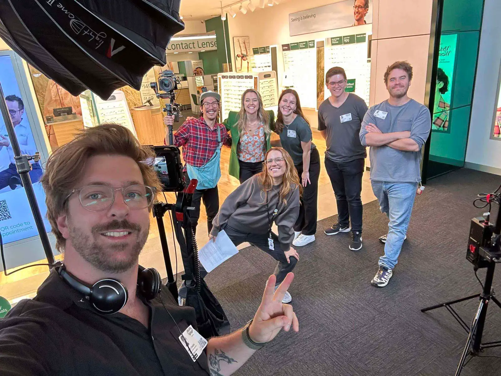 The BTP crew and a Specsavers team grinning for a selfie on set in a Specsavers store